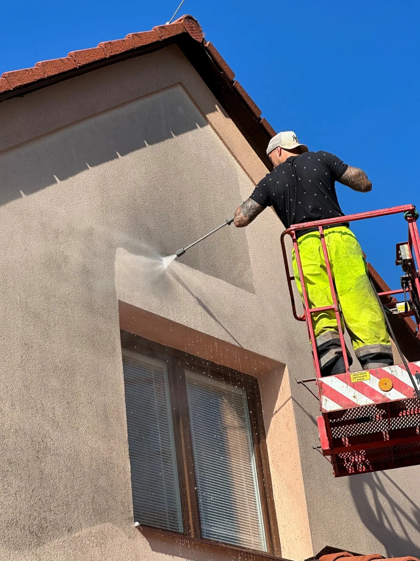 Čištění fasády rodinného domu vysokotlakou tryskou z montážní plošiny.