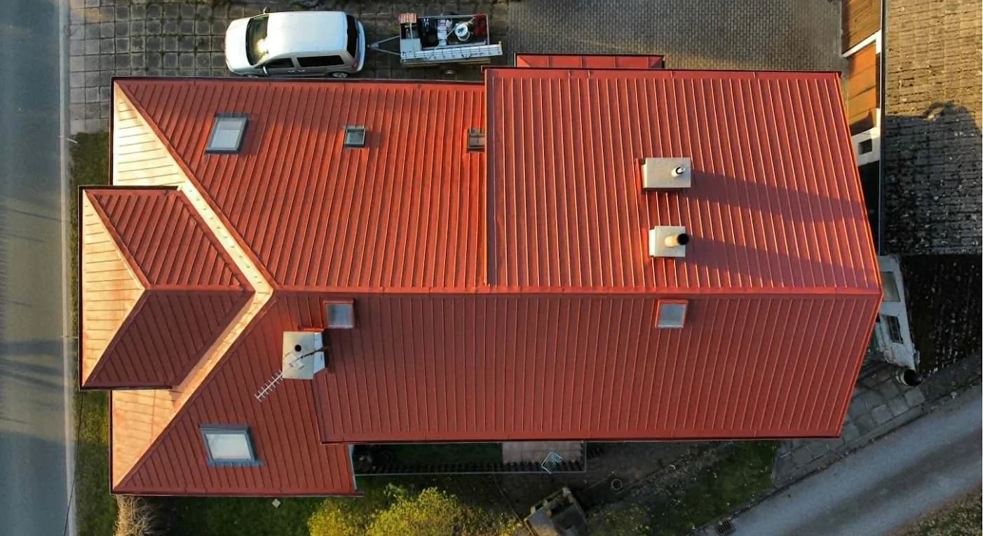 Tatáž střecha po renovaci, sytě červený nátěr, letecký pohled ze stejného místa.